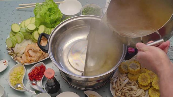 亚洲美食的概念。经验不足的厨师将汤倒入特殊的锅中