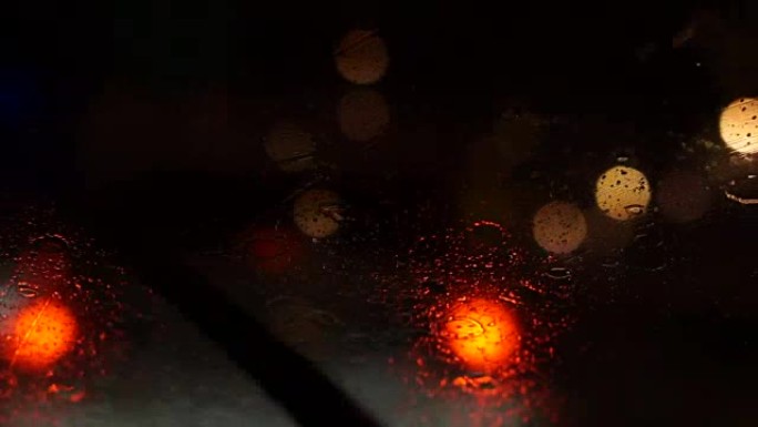 道路上美丽多彩的模糊交通视频。雨水流动和雨刷在汽车前风挡玻璃上