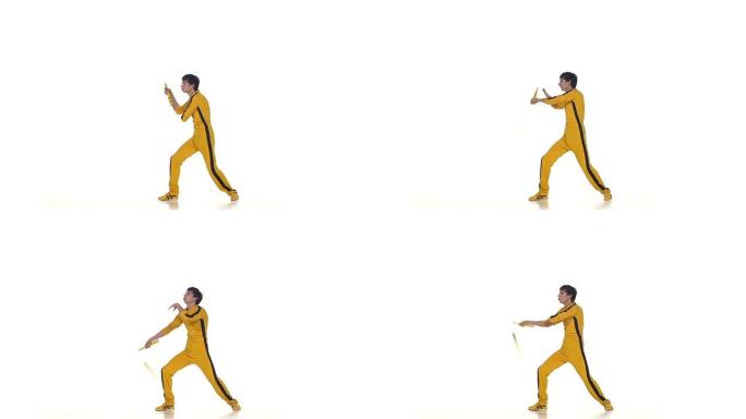 穿着黄色西装的男子训练空手道，熟练地旋转双节棍，慢动作