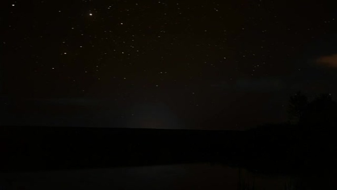 岩石河上夜空中旋转的星星和湖上夜晚的日出旋转的视频大自然睡觉，时光流逝的黄昏，美丽的星星夜晚的流星旋