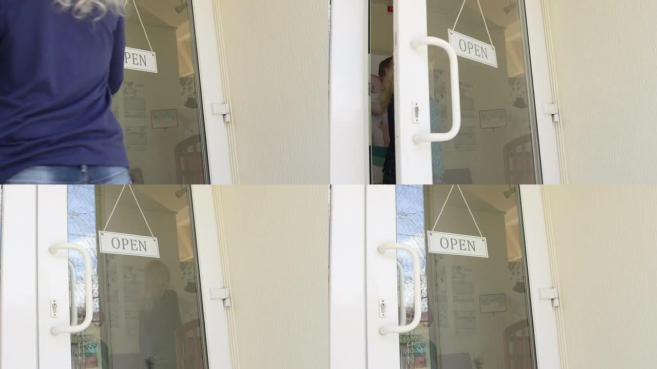 年轻女子打开一家服装店的前玻璃门
