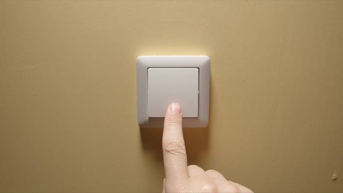 灯熄灭-人手关闭黄色墙壁上的按钮