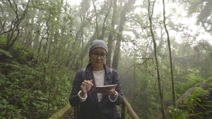 亚洲妇女在雨林中旅行使用数字平板电脑拍照