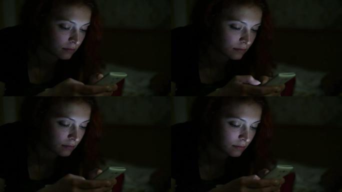 年轻女子晚上在家中躺在床上使用智能手机