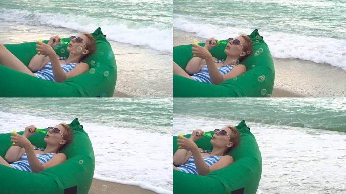 美丽的狡猾女人在海洋海滩上吹肥皂泡