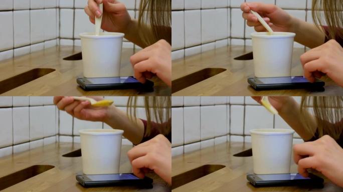 女人在咖啡馆里喝汤并使用智能手机