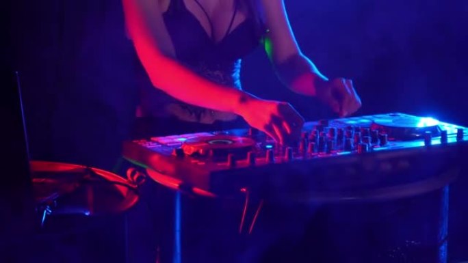 性感的DJ播放音乐，在夜总会的调音台上混音。