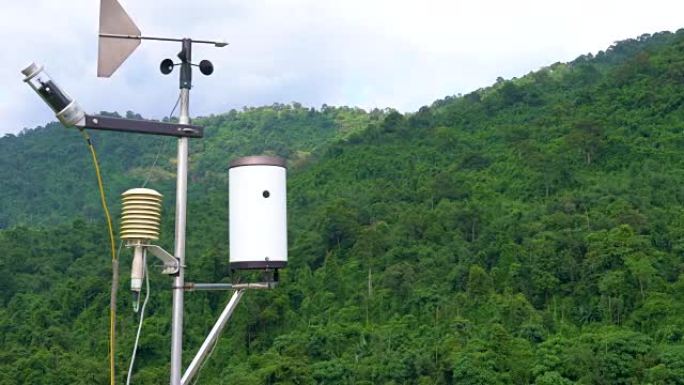 带气象传感器的气象气象站天线，苍白的阴云密布的天空和背景中的森林。