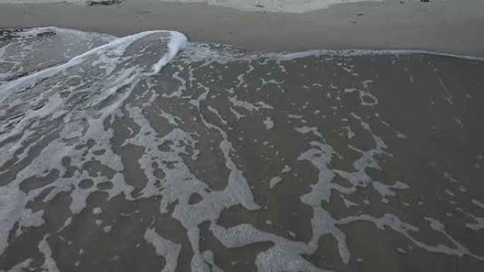 沙滩与海浪覆盖和下降，泡沫表面和螺旋清澈的水