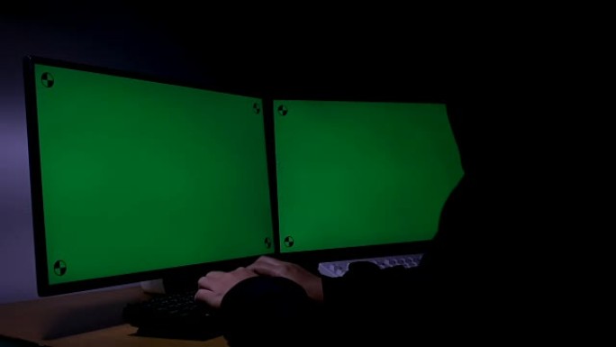 黑客使用计算机扩展绿色宽屏监视器，在黑暗的房间里带有运动跟踪标记，环境声音未来派技术和网络犯罪概念黑