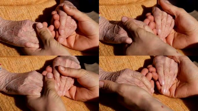 一位年轻的男性双手安慰着奶奶的一双年迈的手在户外特写。