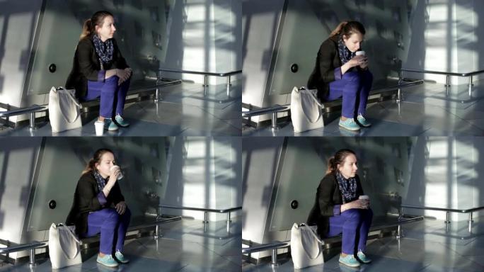 悲伤的女人坐在候机室喝咖啡，等待下一班飞机。