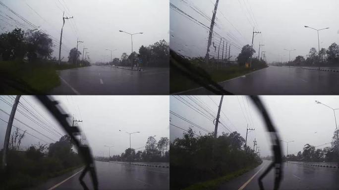 通过带有雨滴的汽车挡风玻璃的道路视图，在雨中行驶。