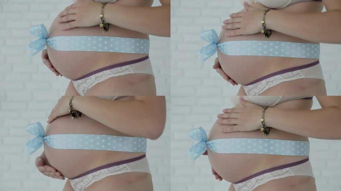 腹部蓝色蝴蝶结的健康孕妇。