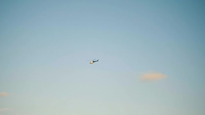 蓝天下飞行巡逻直升机。直升机维护和在空中盘旋。慢动作