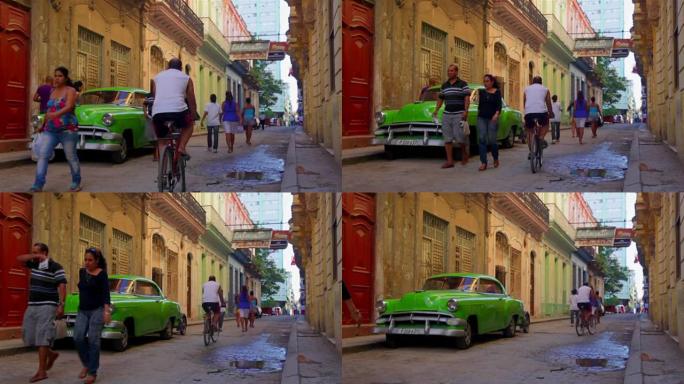 老式绿色汽车停在哈瓦那维耶哈区，人们四处走动