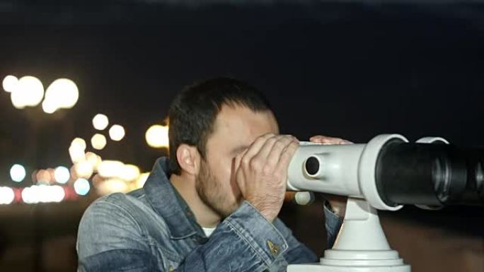 年轻人透过投币双筒望远镜看