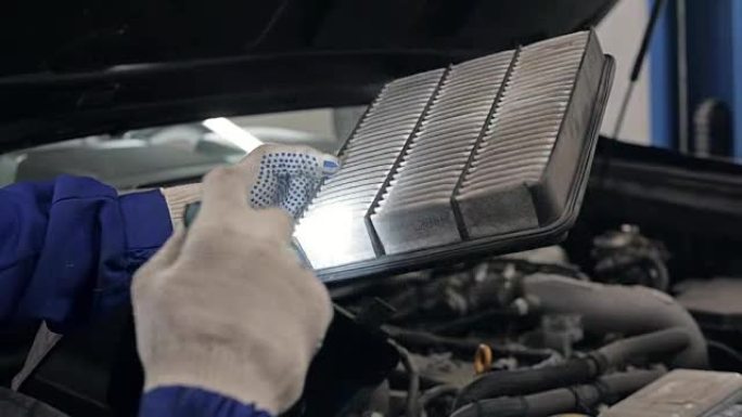 年轻的西班牙裔机械师在汽车商店更换汽车的机油滤清器
