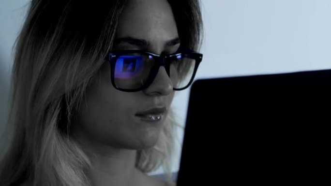 午夜时分，戴着眼镜的女人在笔记本电脑上工作的特写镜头