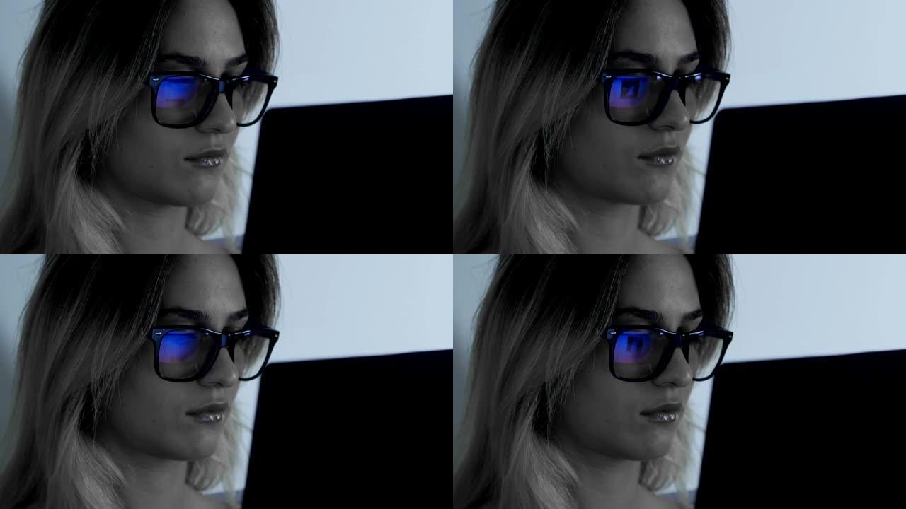 午夜时分，戴着眼镜的女人在笔记本电脑上工作的特写镜头