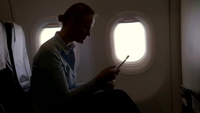 在飞机视图中，使用智能手机和加密狗扫描银行卡用银行卡付款的女人