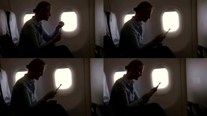 在飞机视图中，使用智能手机和加密狗扫描银行卡用银行卡付款的女人