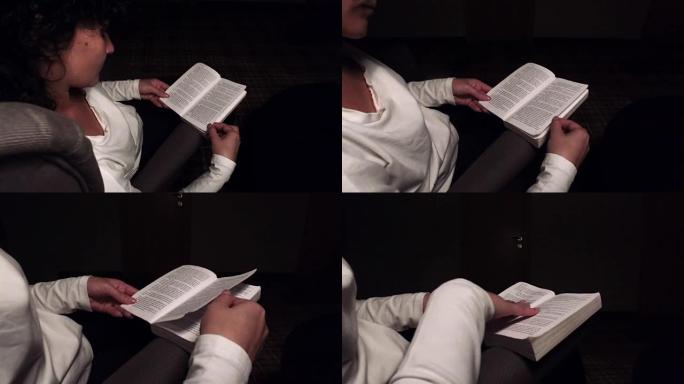 年轻女子坐在家里的现代椅子上，在客厅看书放松