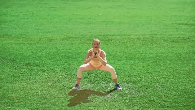苗条的运动女人在绿草地上锻炼