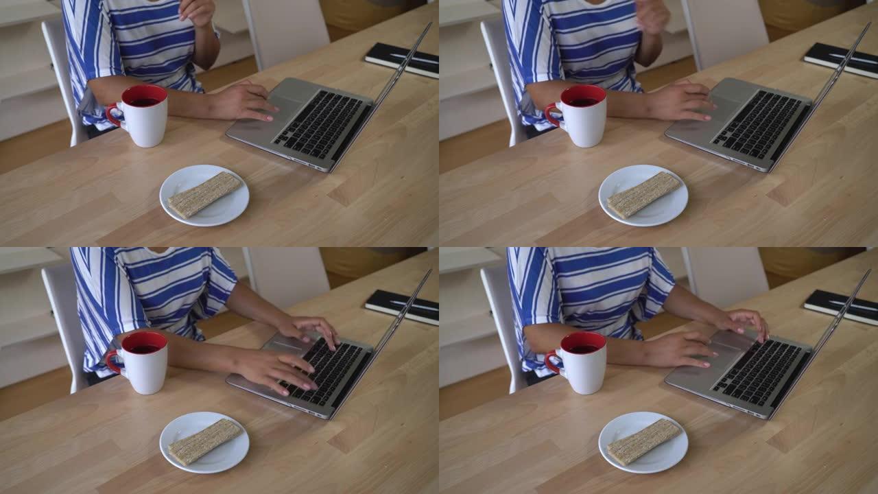 无法识别的女人在电脑上打字并吃零食