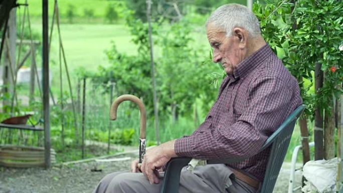 疲惫的老人独自坐在户外的乡村绿色背景