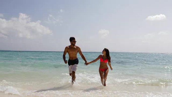 暑假里，海滩上的人们牵着手从水里奔跑，快乐的男人和女人恋爱了