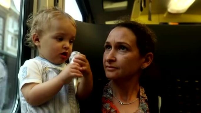 宝贝在火车上大笑。妈妈和宝宝一起坐火车旅行。婴儿把物体放在嘴里
