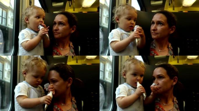 宝贝在火车上大笑。妈妈和宝宝一起坐火车旅行。婴儿把物体放在嘴里