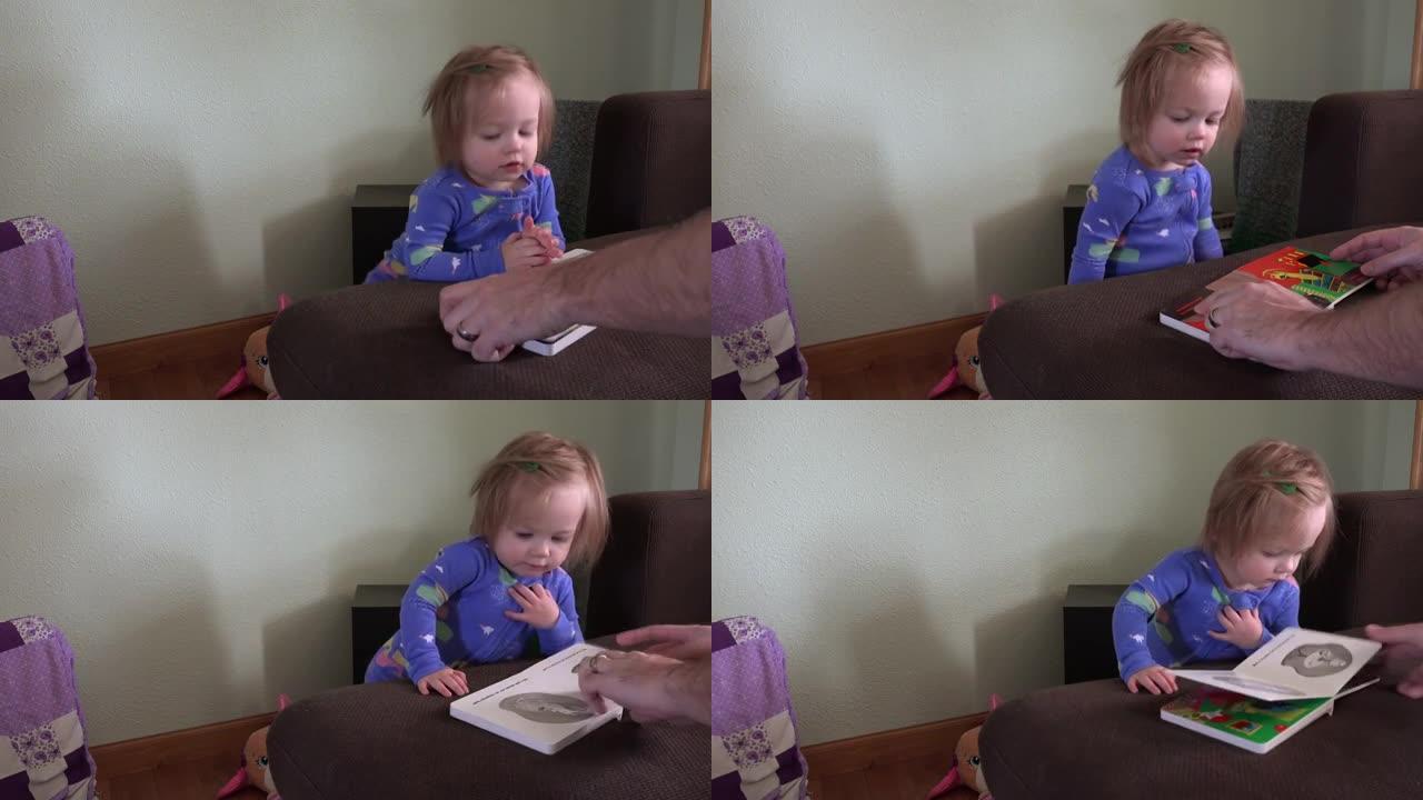 爸爸和穿着蓝色睡衣的蹒跚学步的女孩一起读书。用索尼PXW-Z100 UHD相机制作的4k视频，分辨率