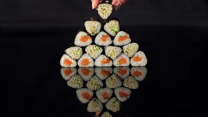 手把寿司放在黑色背景的金字塔上。