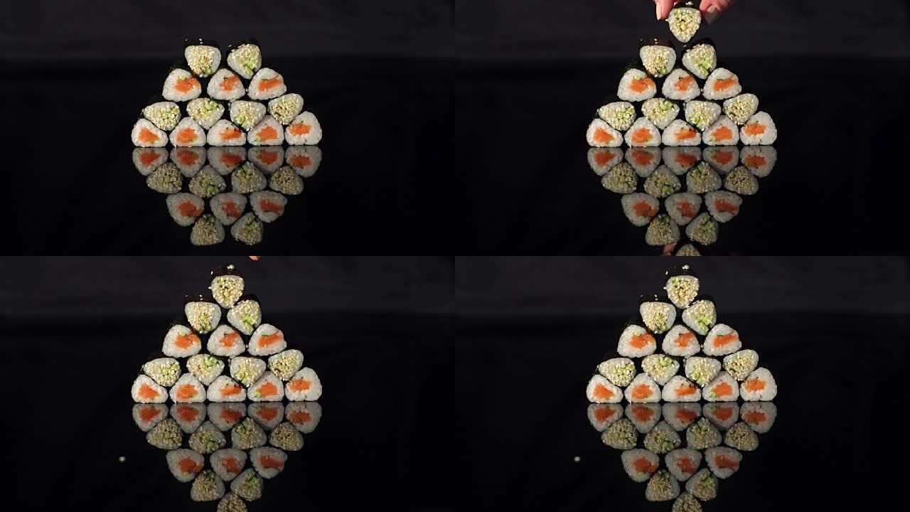 手把寿司放在黑色背景的金字塔上。