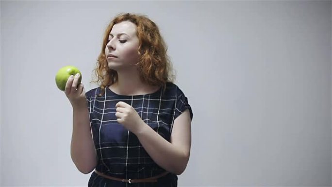 女人在灰色背景下吃青苹果