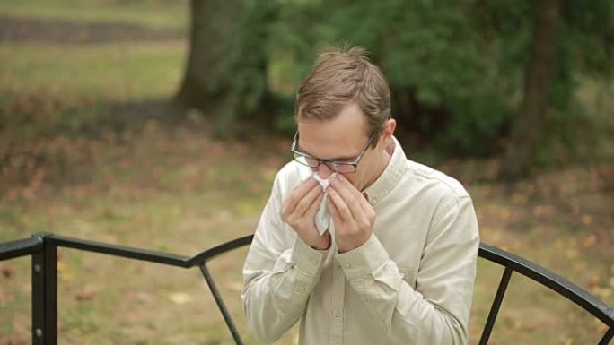 鼻子上拿着手帕的年轻人。一个男人得了重感冒