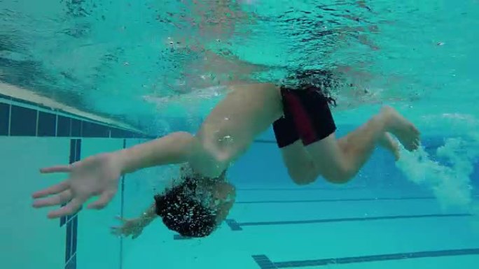年轻的亚洲男孩自由式游泳并翻滚