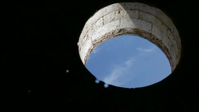 在圆形窗口的水中反射，在该窗口中可以看到天空。静水和漂浮物轻球。摩洛哥El Jadida葡萄牙要塞的