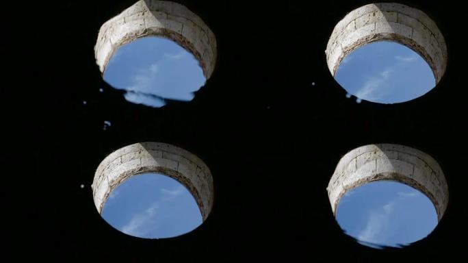 在圆形窗口的水中反射，在该窗口中可以看到天空。静水和漂浮物轻球。摩洛哥El Jadida葡萄牙要塞的