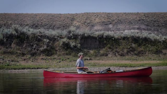 留着小胡子的人在河里的红色独木舟里钓鱼，像多莉一样运动