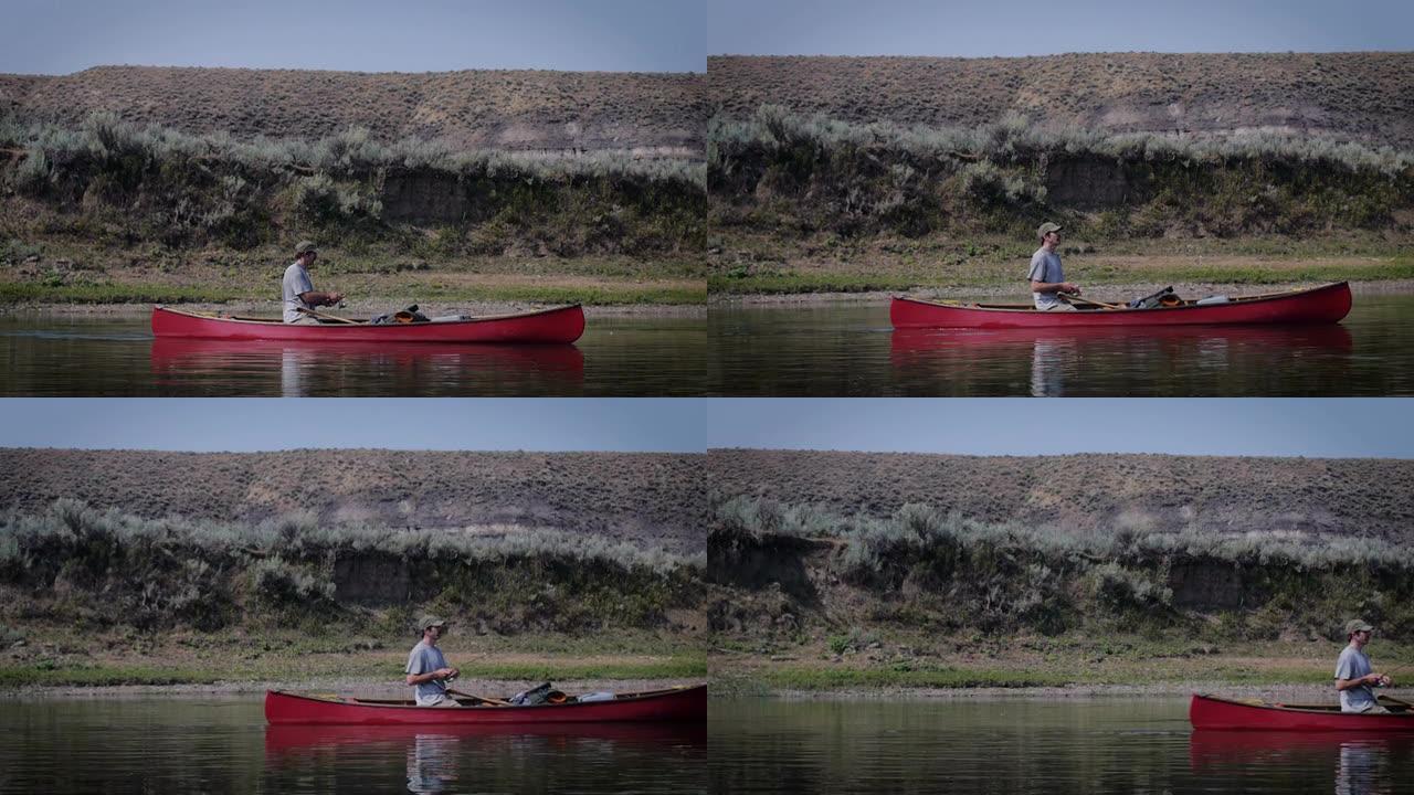 留着小胡子的人在河里的红色独木舟里钓鱼，像多莉一样运动