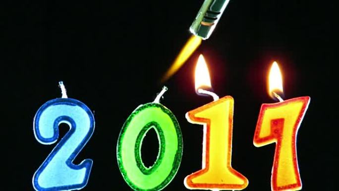 火炬火焰点燃数字形状的蜡烛，庆祝新年2017到来，隔离在黑色背景下