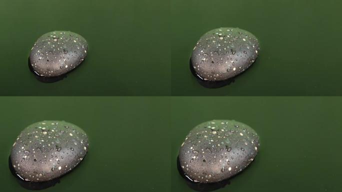 一滴水落在绿色的水和黑色的石头上