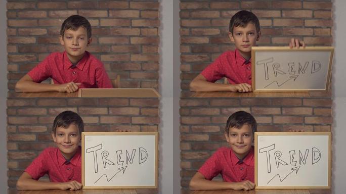 孩子坐在办公桌前拿着挂图，背景红砖墙上刻字趋势