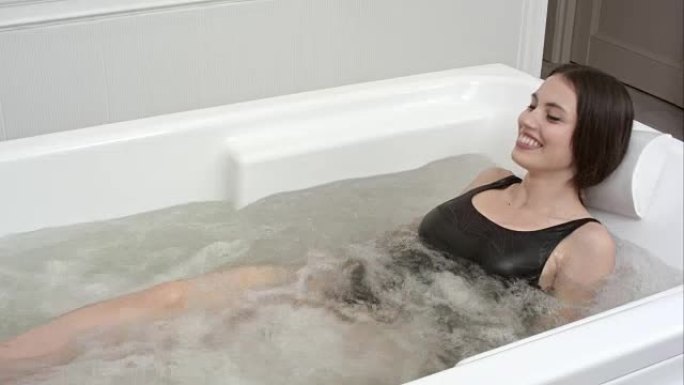 快乐的年轻女子在热水浴缸水疗中心放松