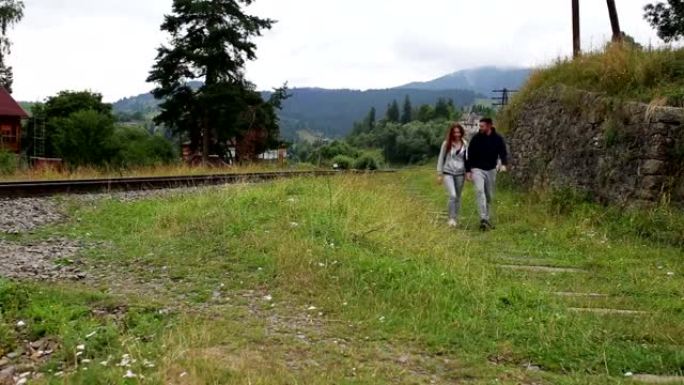 美丽的夫妇一起走在山上的铁路上