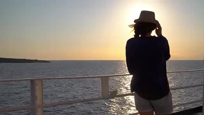 年轻迷人的女人在海上巡航船上观看日落的剪影
