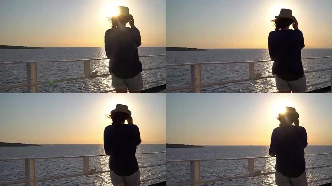 年轻迷人的女人在海上巡航船上观看日落的剪影